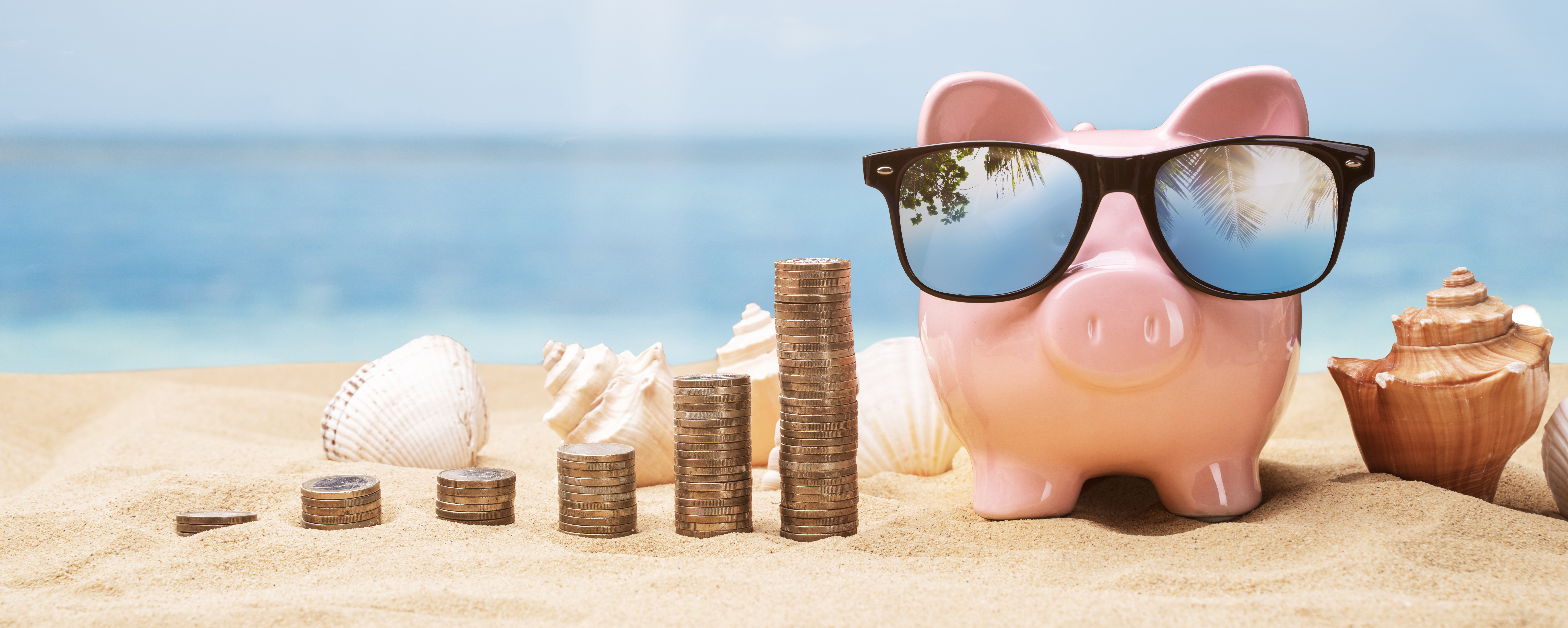 A piggy bank with sunglasses on a beach